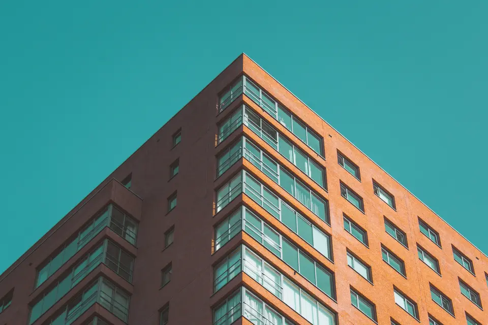 Woontoren met rode gevel en balkons tegen een blauwe lucht